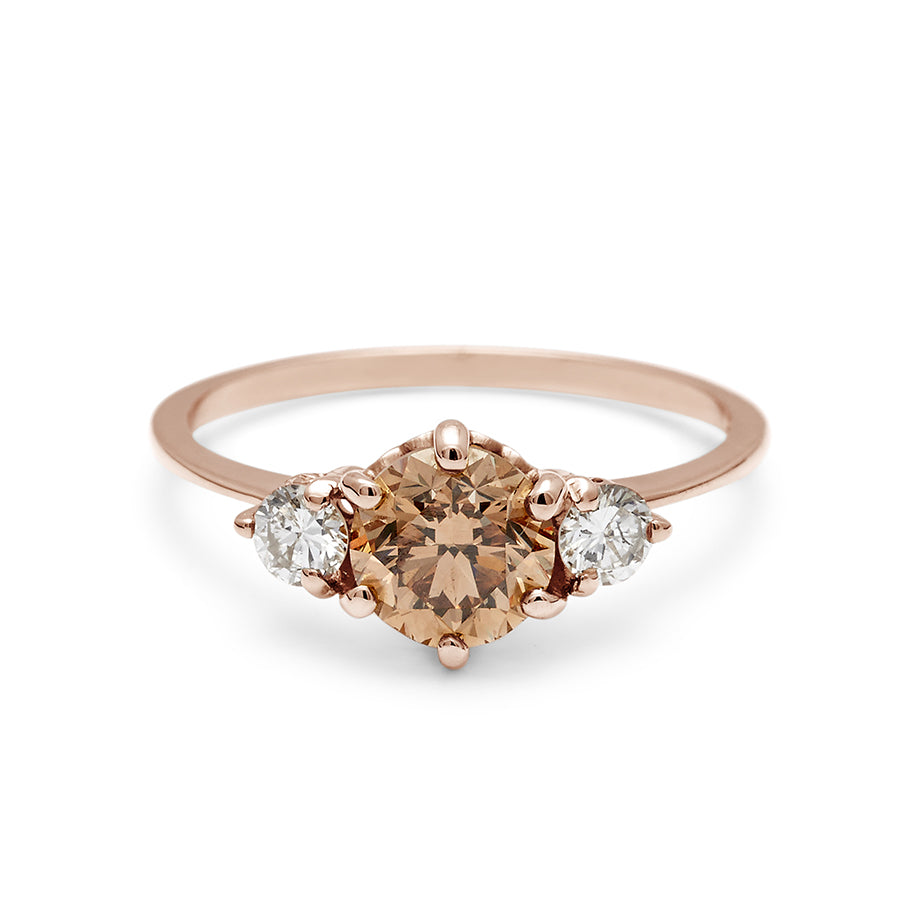 A three stone engagement ring with a round shape champagne diamond center stone with two white diamond round side stones set in rose gold., Rose Gold