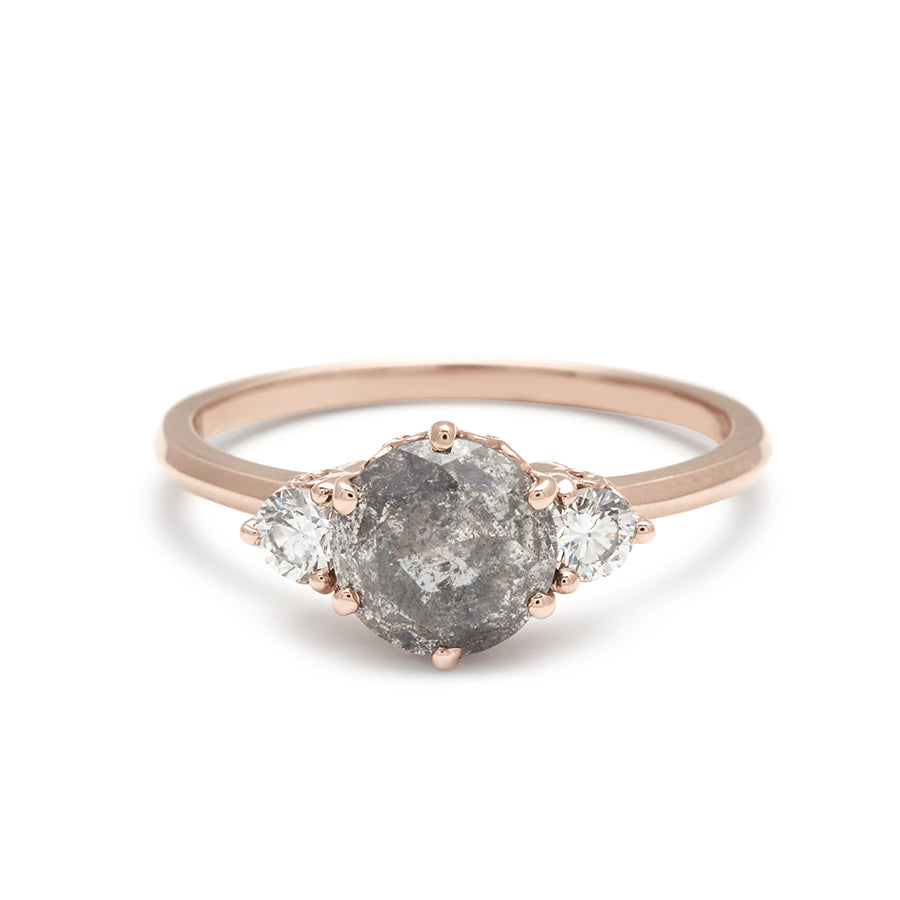 A three stone engagement ring with a round shape grey diamond center stone with two white diamond round side stones set in a rose gold band., Rose Gold