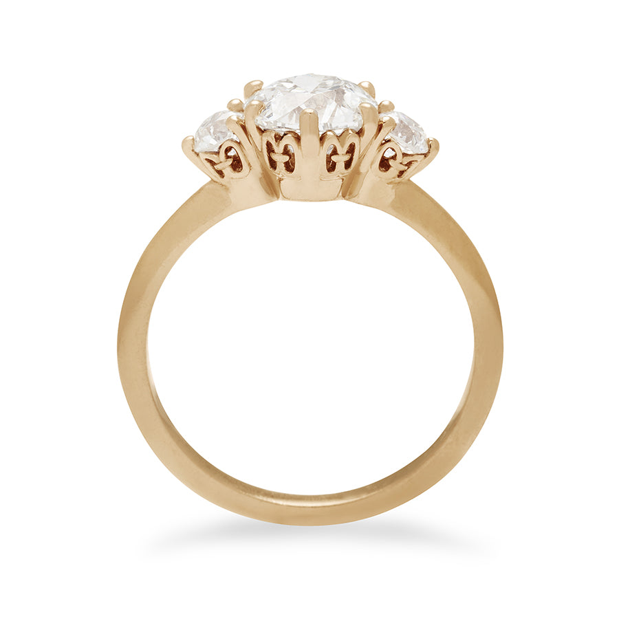 Side view of a three stone engagement ring with a round shape white diamond center stone with two white diamond round side stones set in yellow gold.