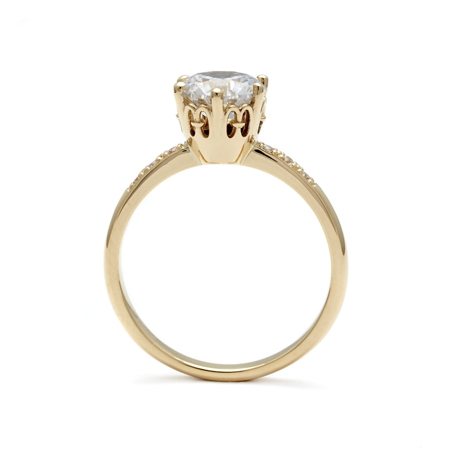 Side view of a solitaire ring with a round brilliant cut white diamond with white diamond pave on either side set in yellow gold., Yellow Gold