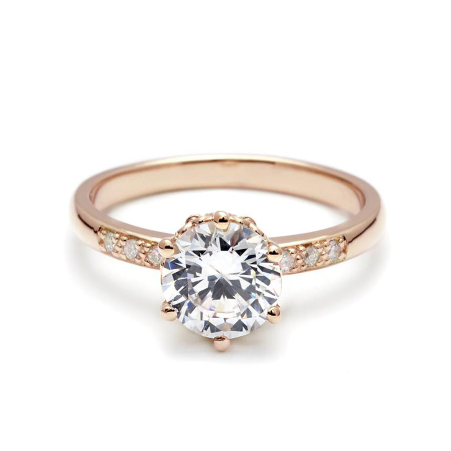 A solitaire ring with a round brilliant cut white diamond with white diamond pave on either side set in rose gold., Rose Gold