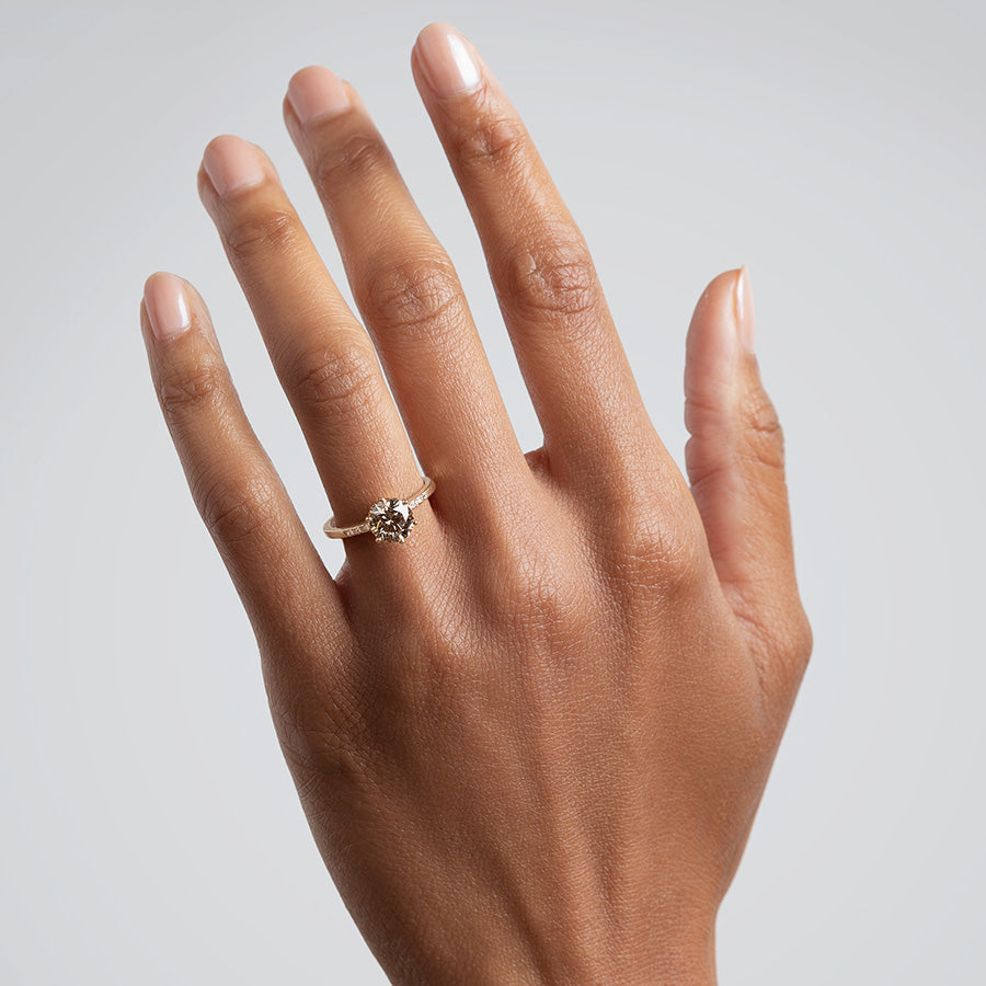 A solitaire ring with a round 1.50ct champagne diamond with white diamond pave on either side set in yellow gold on a medium-complexion on a ring finger., Rose Gold, Yellow Gold