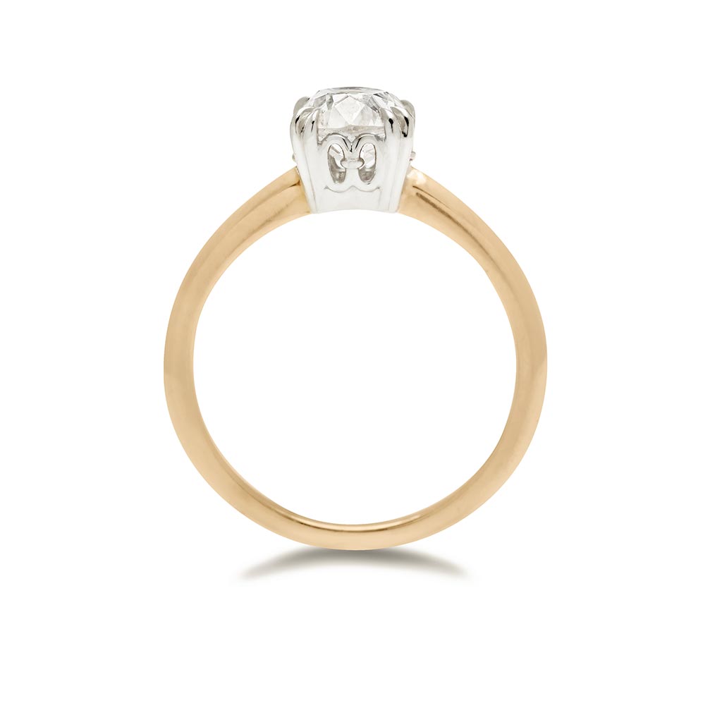 Side view of a solitaire ring cushion cut white diamond set in white gold basket and a knife edge yellow gold band.