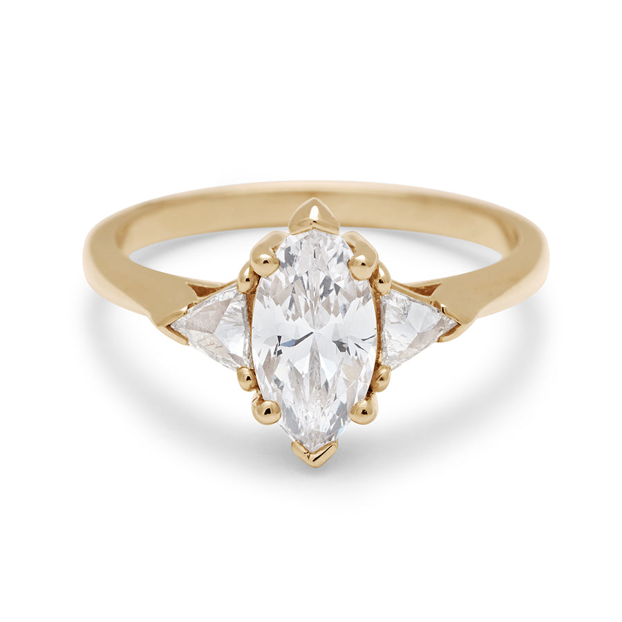 A three stone engagement ring with a marquise shape brilliant cut 1.00ct white diamond center stone with two white diamond trillion side stones set in yellow gold., Yellow Gold