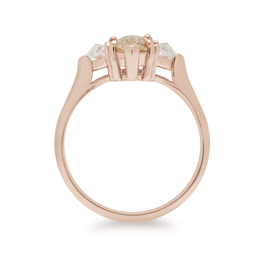 Side view of a three stone engagement ring with a marquise shape 0.85ct champagne diamond center stone with two white diamond trillion side stones set in rose gold.