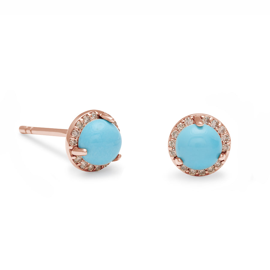 A pair of medium turquoise center stone earrings with a halo of champagne diamond set in rose gold one earring angled.