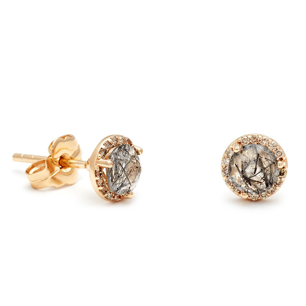 A pair of medium black rutilated quartz center stone earrings with a halo of champagne diamond set in yellow gold one earring angled.