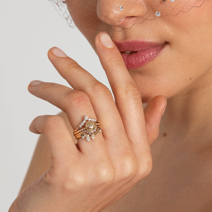 A band with white diamonds in ascending size set in yellow gold above a solid gold gemstone ring and two diamond dusted curve bands.
