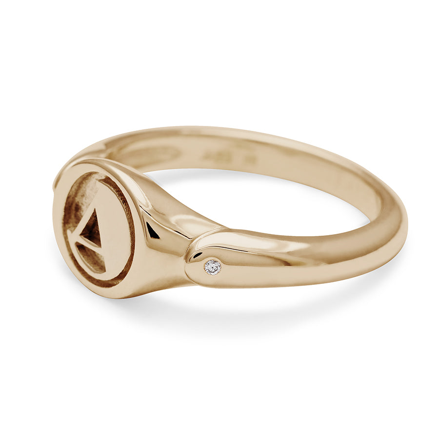 Angled view of a monogrammed signet ring with an "A" on the front and two white diamond accents on either side and set in yellow gold.