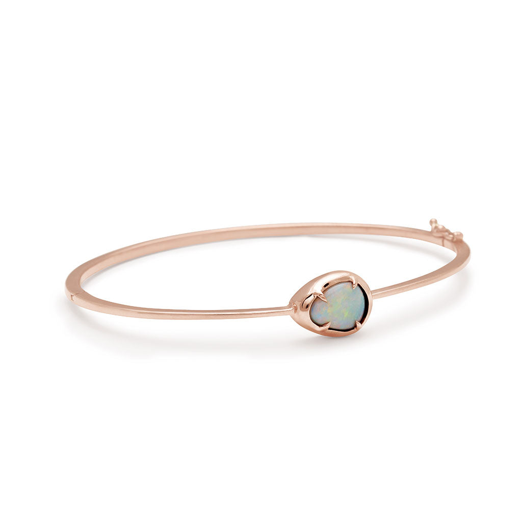 Angled view of a bracelet with an opal center stone set in bezel with claw prongs all set in rose gold.