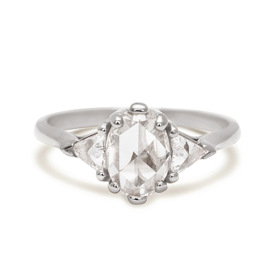 A three stone engagement ring with an opal shape white diamond center stone with two white diamond trillion side stones set in white gold.