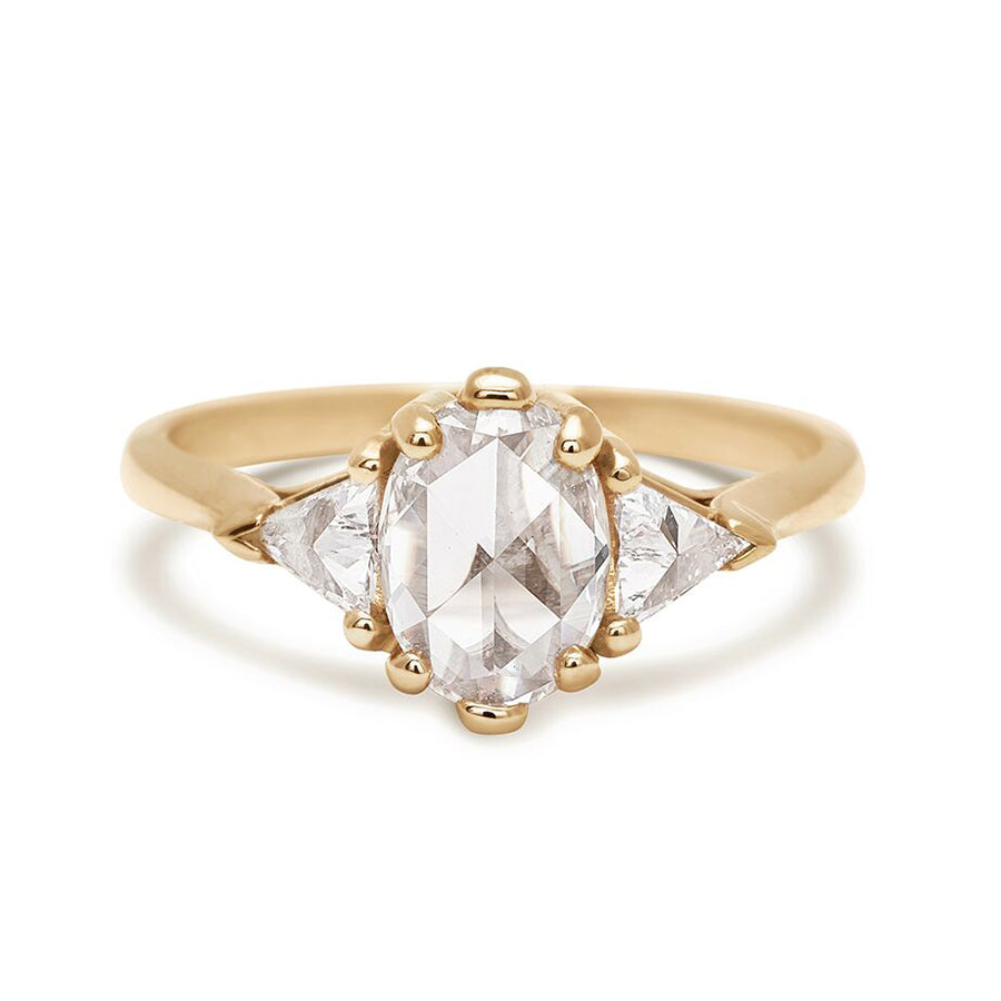 A three stone engagement ring with an opal shape white diamond center stone with two white diamond trillion side stones set in yellow gold.
