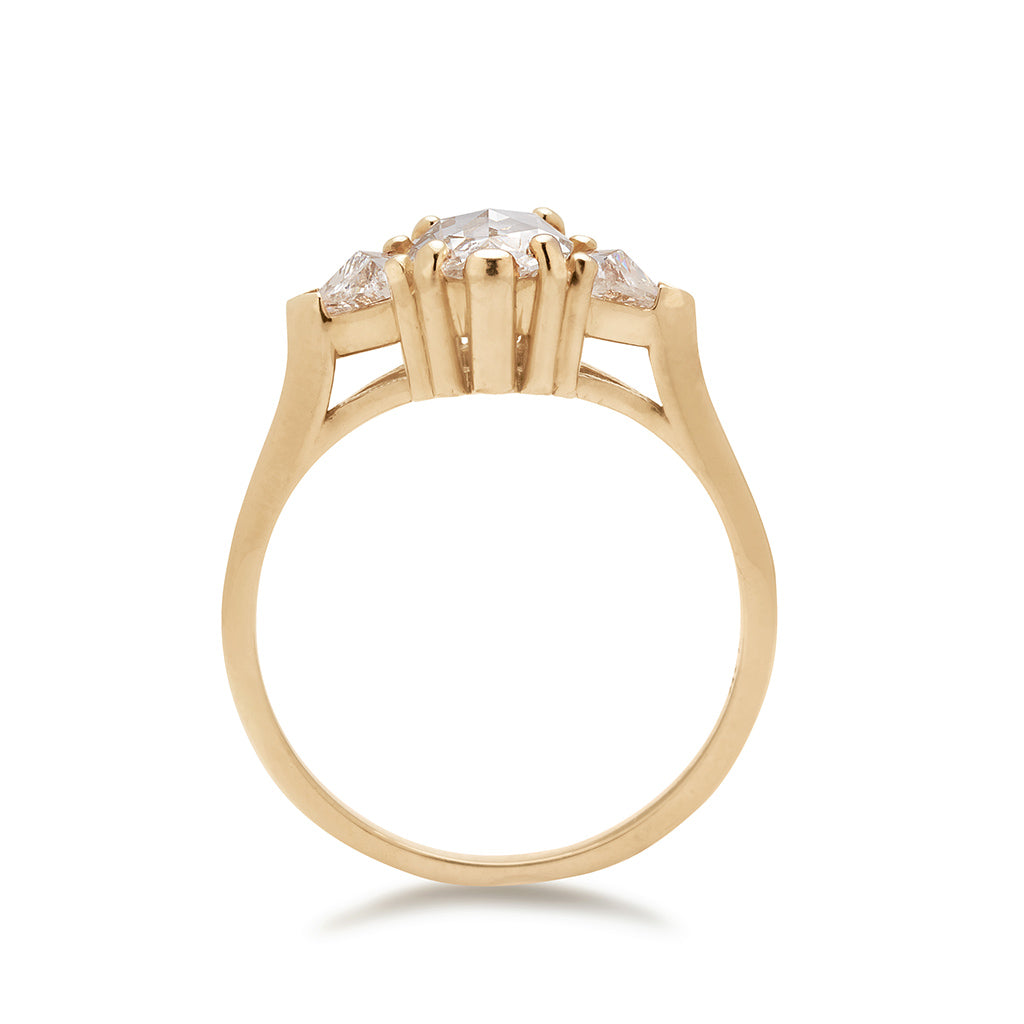 Side view of a three stone engagement ring with an opal shape white diamond center stone with two white diamond trillion side stones set in yellow gold.