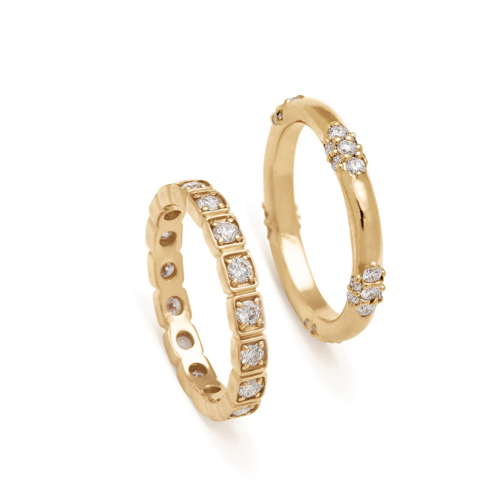 A 3mm white diamond eternity band set in yellow gold next to a five cluster white diamond band in white gold.