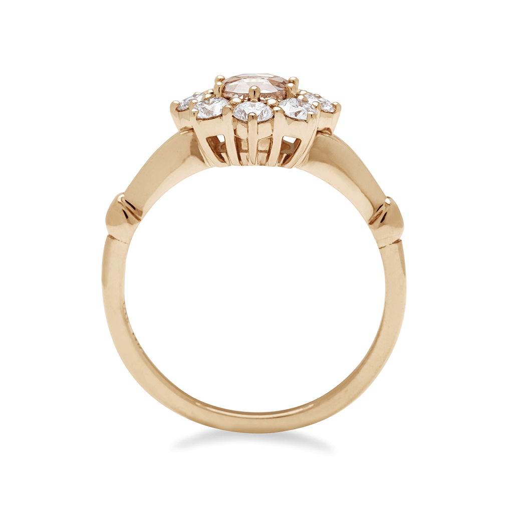 Side view of a cluster engagement ring with a rose cut champagne diamond center stone and round white diamond stones surrounding it set in yellow gold.