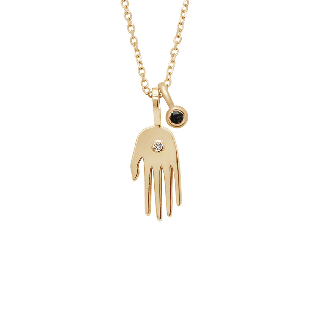 A small hand charm in yellow gold with a white diamond accent stone and a bezel set black diamond charm in yellow gold on a yellow gold chain.