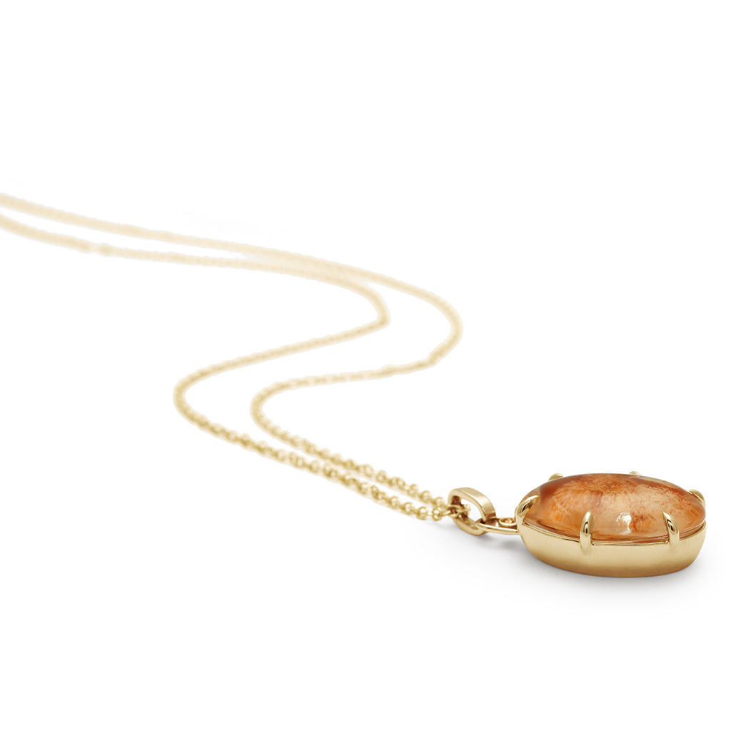 Side view of a quartz charm in a bezel setting with claw prongs set in yellow gold with champagne diamond accent stone on a yellow gold chain.