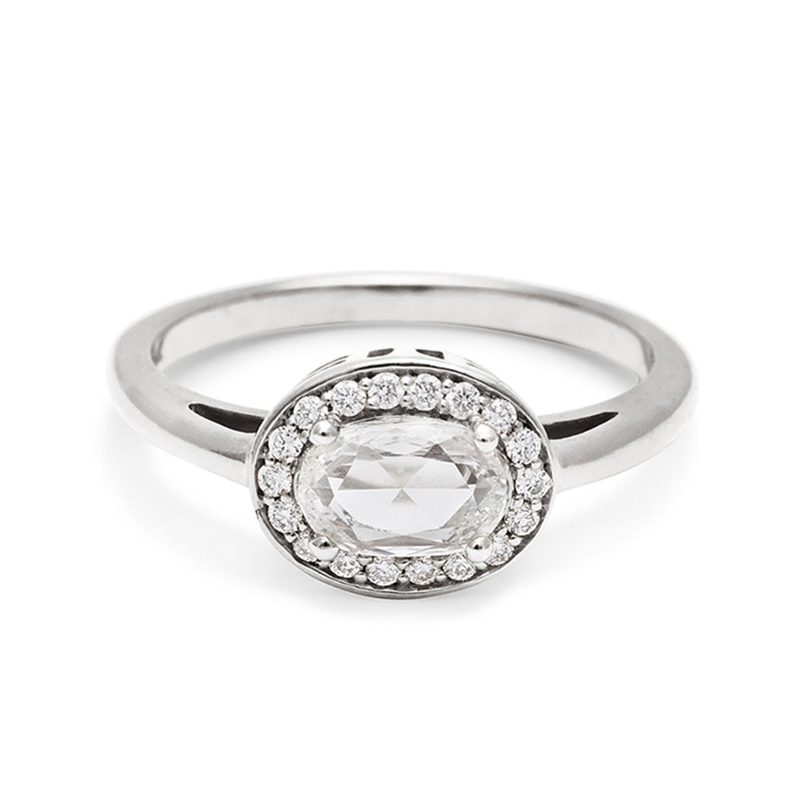 An engagement ring with a rose cut and oval shape white diamond center stone surrounded by a white diamond pave halo set in white gold., White Gold