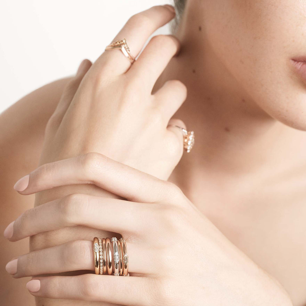 Three straight band with 5 clusters white diamond band set in yellow gold on a light-complextion models ring finger.