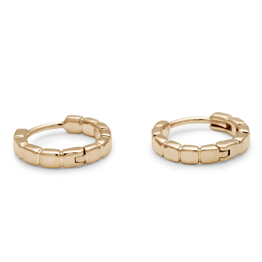 Side view of a solid gold pair of huggie hoops set in yellow gold.