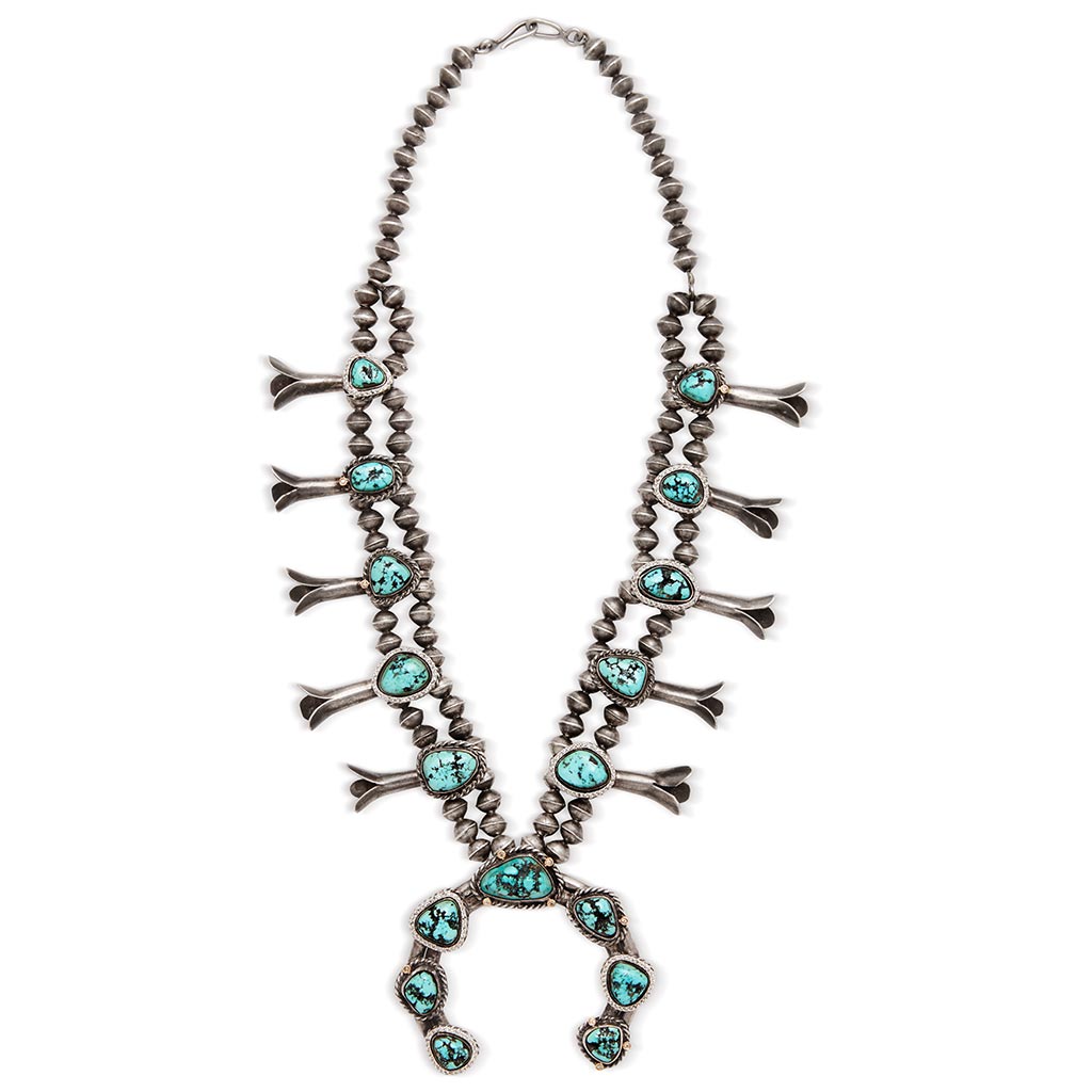 Side view of a turquoise stone squash blossom necklace set in sterling silver.