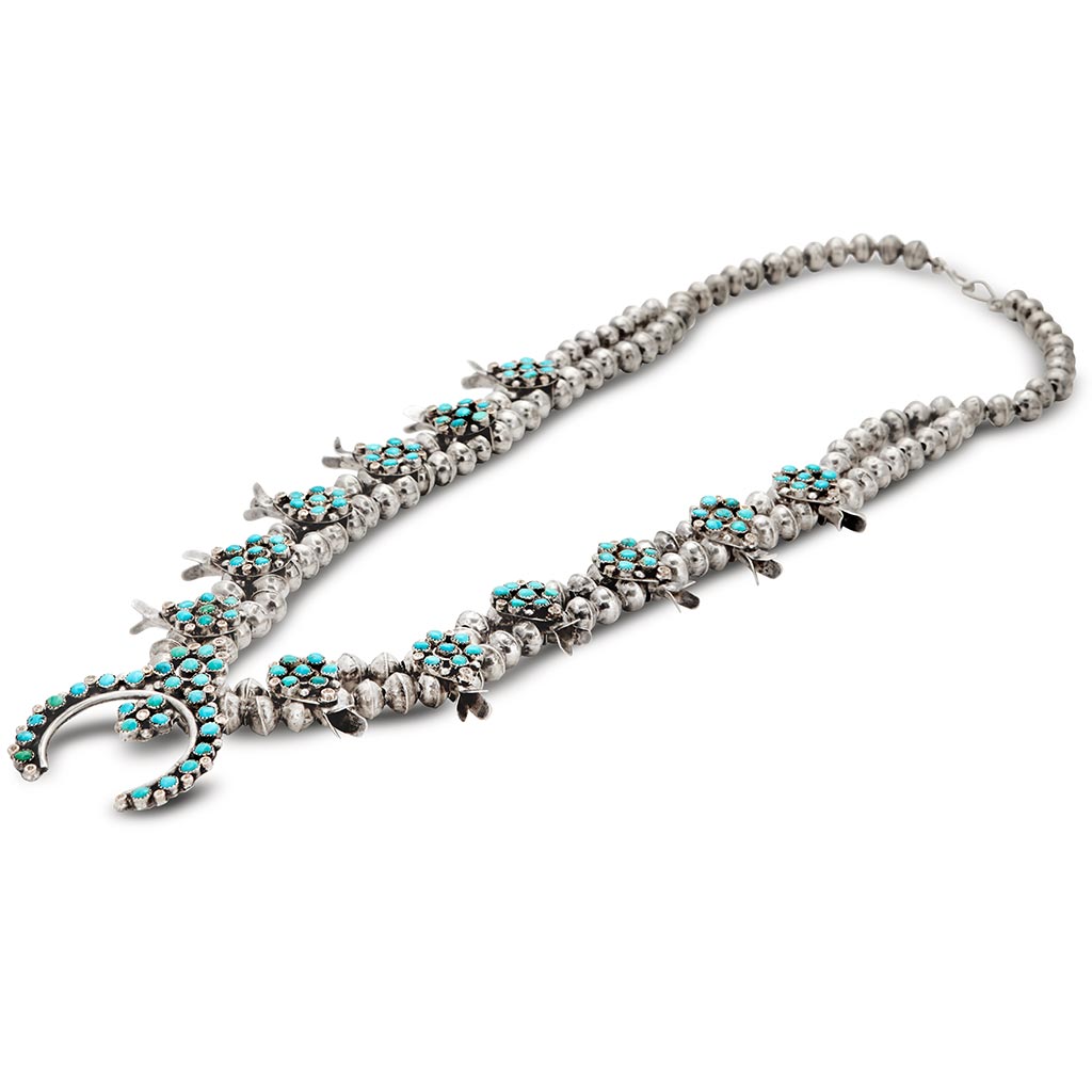 Side view of a turquoise stone squash blossom necklace set in sterling silver.