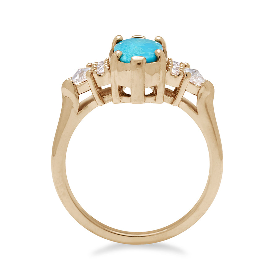 A side view of an oval shape turquoise center stone ring with three round white diamonds on either and two white diamond trillions on the outer edges of each side set in yellow gold.
