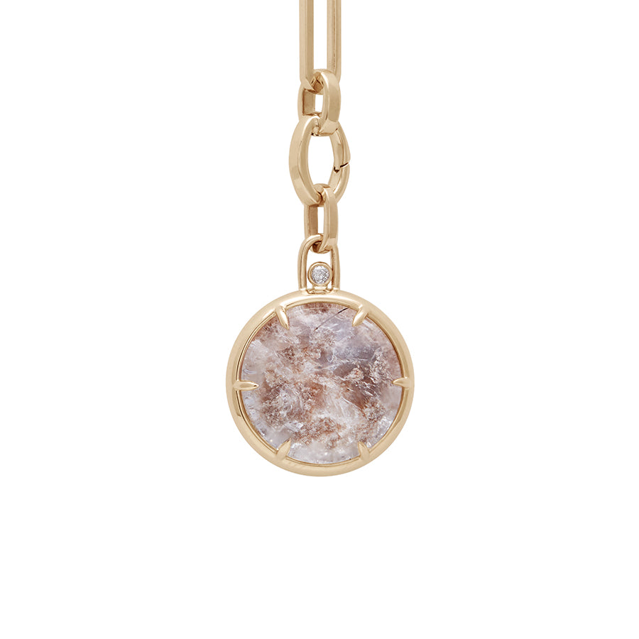 Zoomed in view of a quartz charm with a desert like scene in a bezel setting with claw prongs set in yellow gold with white diamond accent stone on a mixed link yellow gold chain.