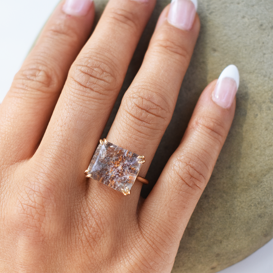 A square quartz solitaire ring set in yellow gold on a medium-complextion ring finger.