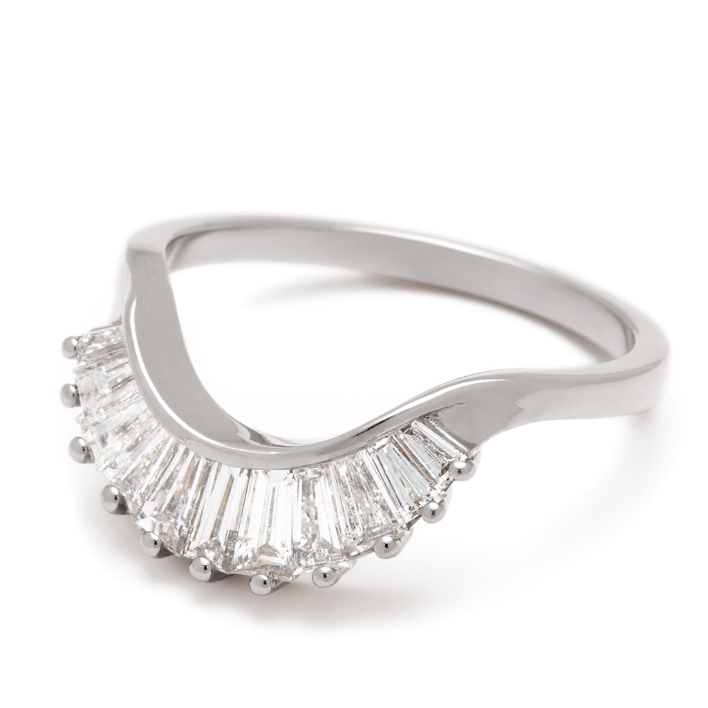 Angled view of 11 white diamond baguettes set in a curved band and in white gold.