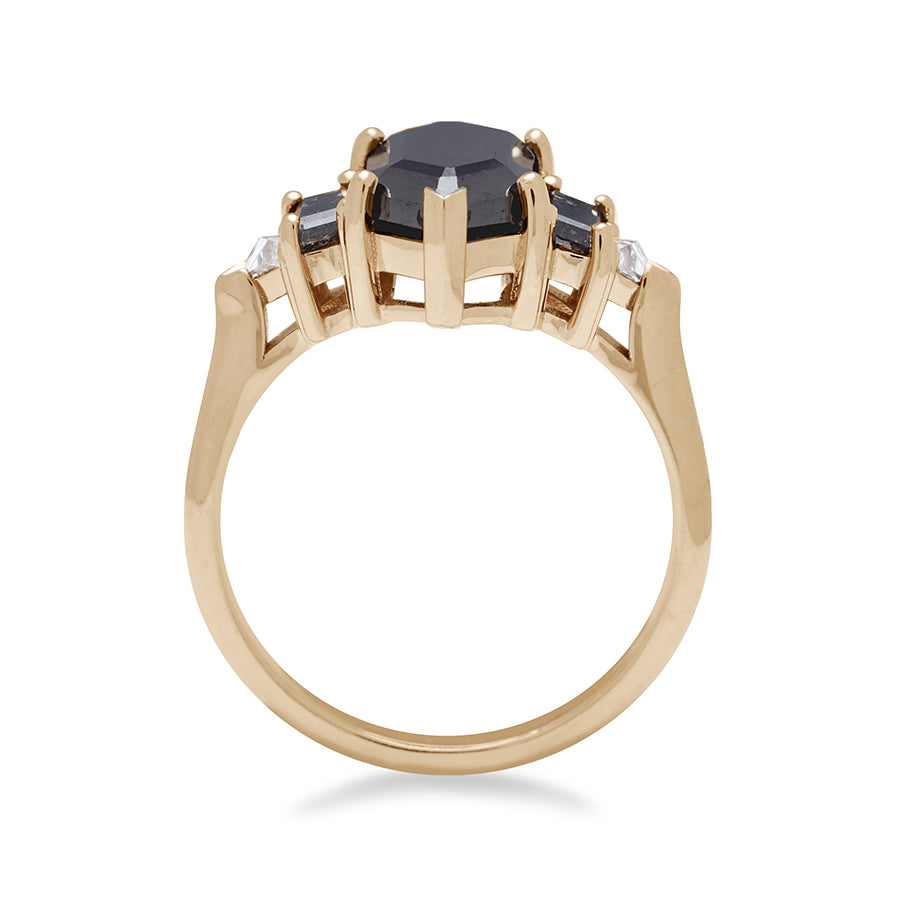 Side view of a ring with a hexagonal shaped black diamond center stone with one baguette black diamond and one white diamond trillion on either side set in yellow gold.