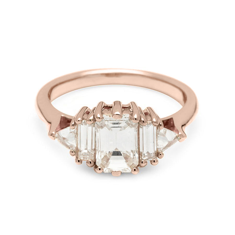 A ring with an emerald cut and shaped 1.00ct white diamond center stone with one baguette white diamond and one white diamond trillion on either side set in rose gold., Rose Gold
