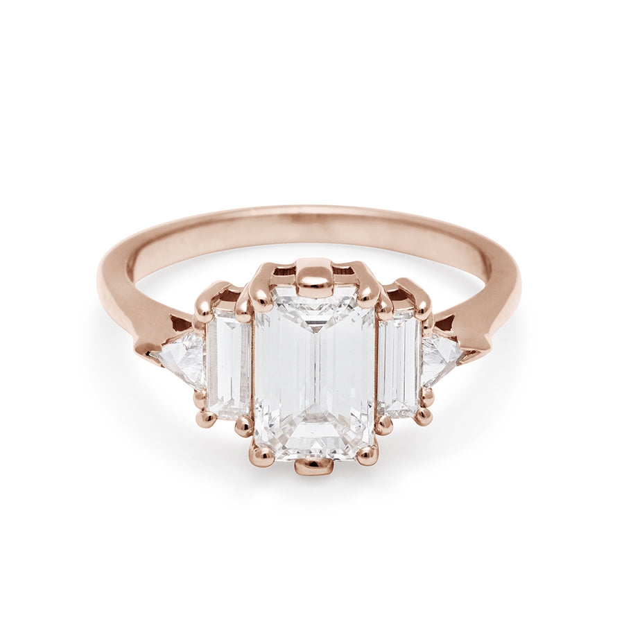 A ring with an emerald cut and shaped 1.50ct white diamond center stone with one baguette white diamond and one white diamond trillion on either side set in rose gold., Rose Gold