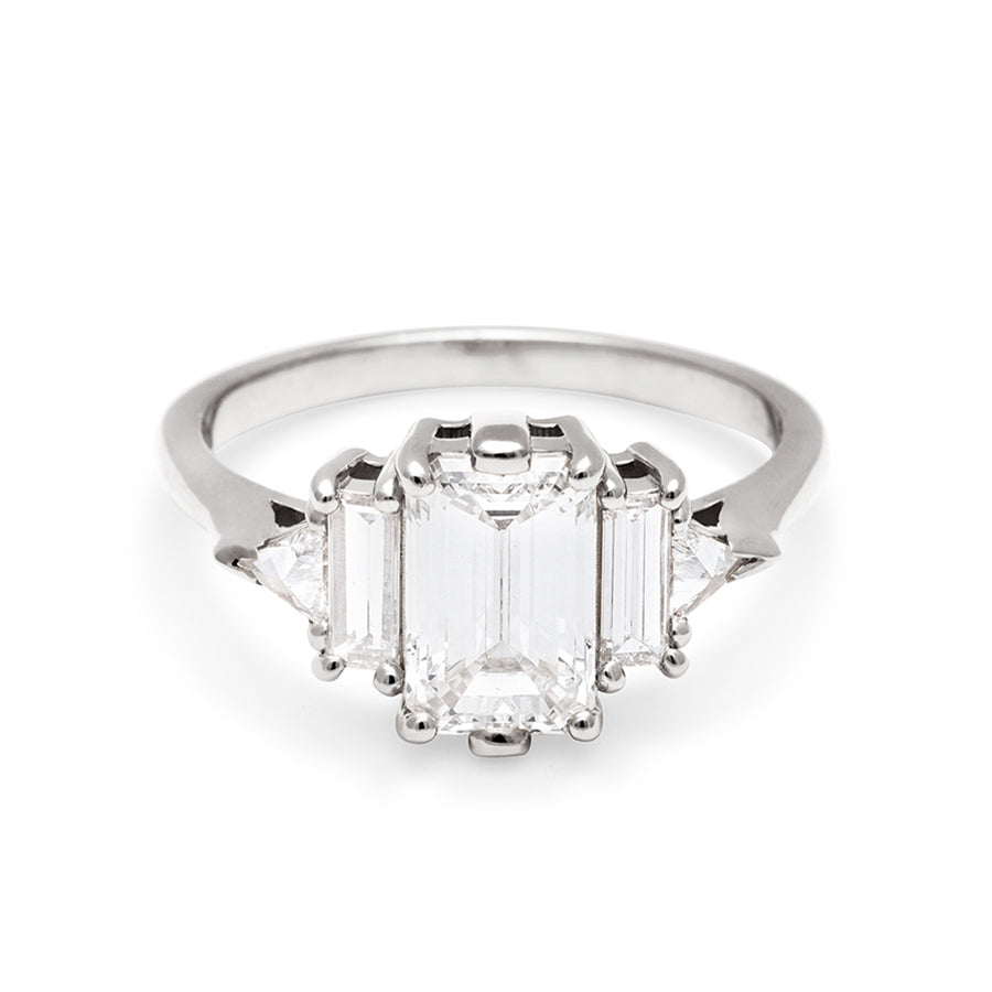 A ring with an emerald cut and shaped 1.50ct white diamond center stone with one baguette white diamond and one white diamond trillion on either side set in white gold., White Gold