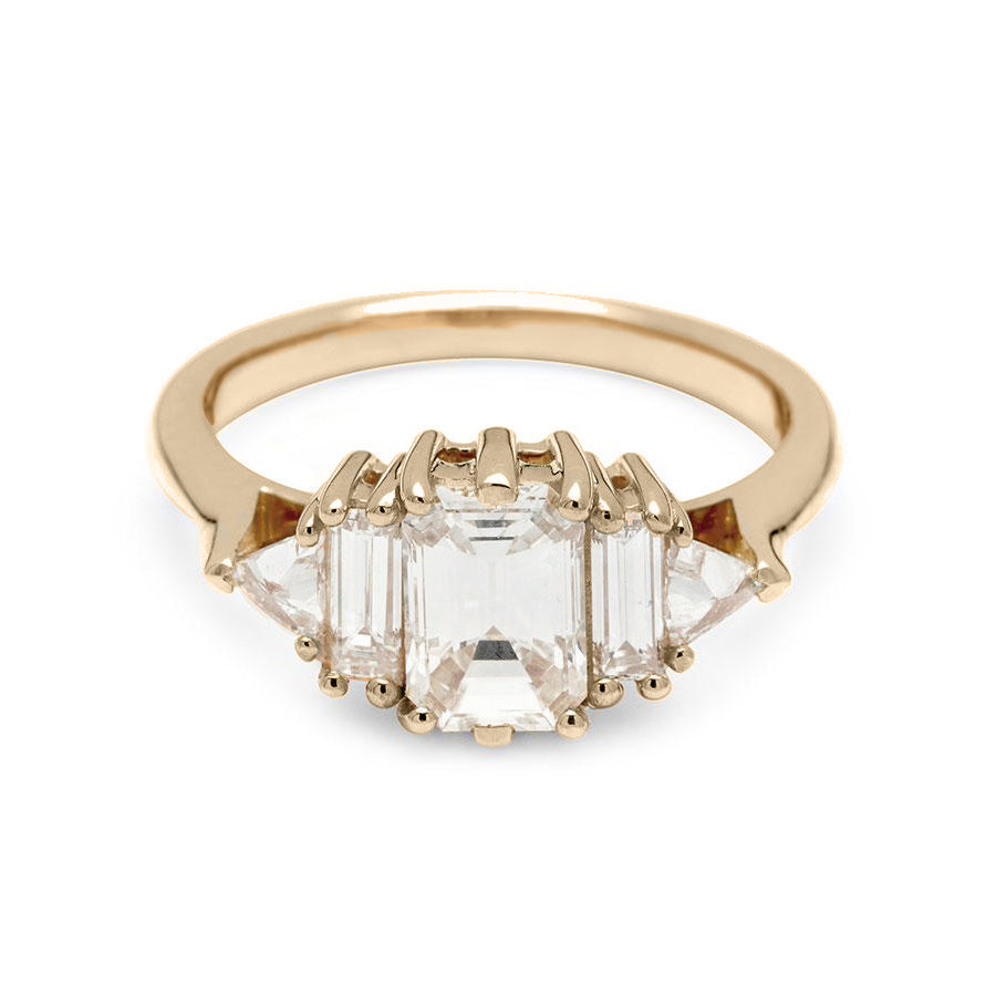 A ring with an emerald cut and shaped 1.00ct white diamond center stone with one baguette white diamond and one white diamond trillion on either side set in yellow gold., Yellow Gold