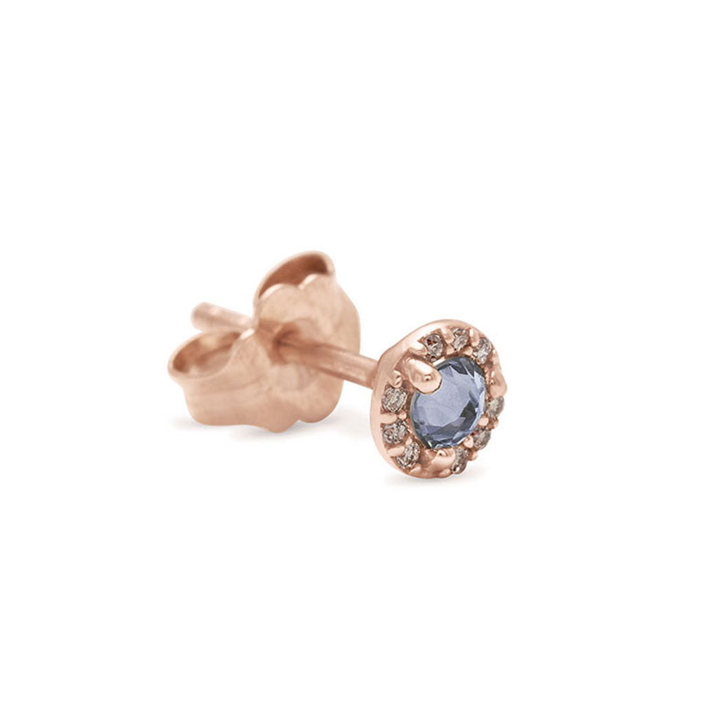 A single tiny grey spinel center stone earring with a halo of white diamond set in rose gold.