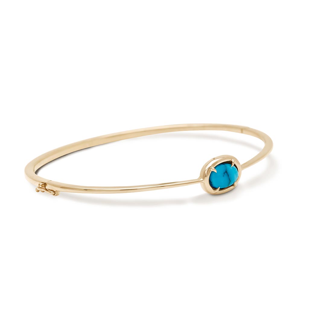 Angled view of a a bracelet with a bezel set turquoise stone with claw prongs set in yellow gold.