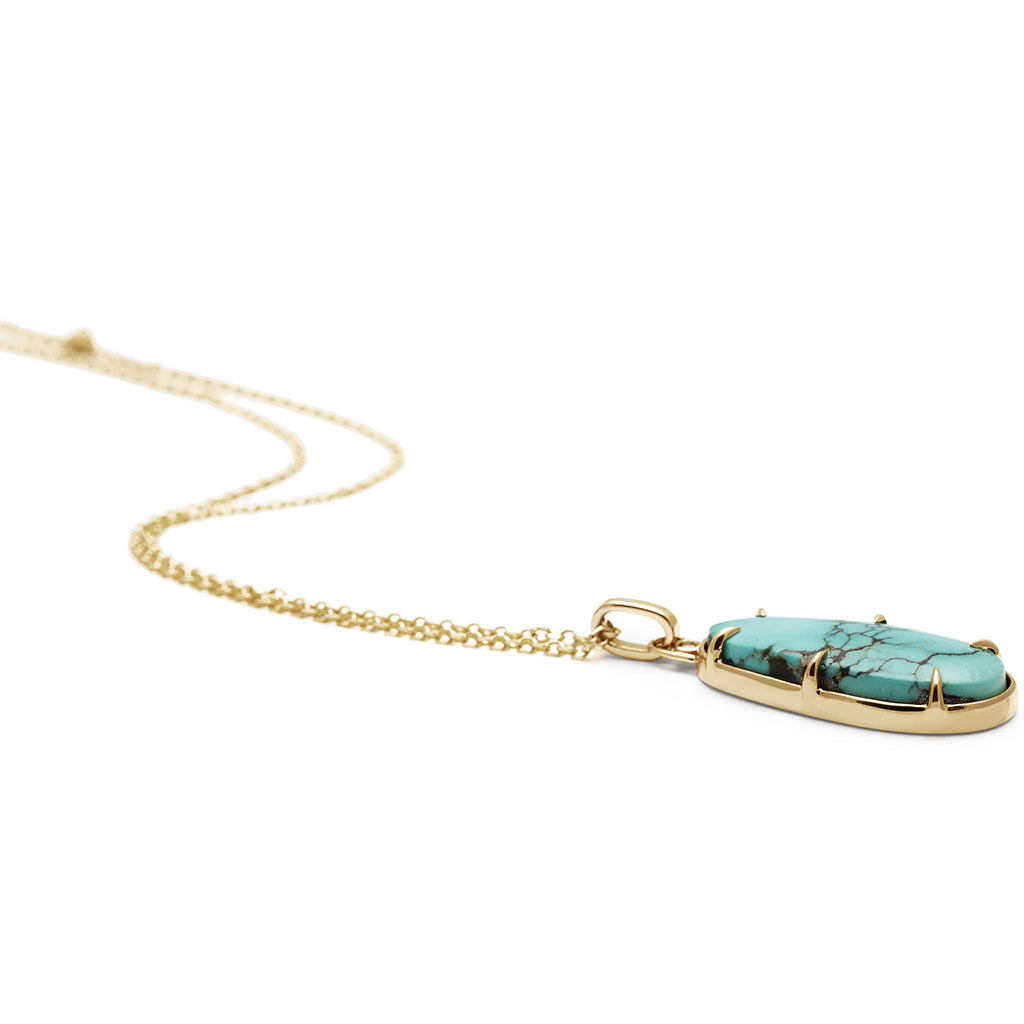 Size view of a turquoise charm in a bezel setting with claw prongs set in yellow gold with grey diamond accent stone on a yellow gold chain.