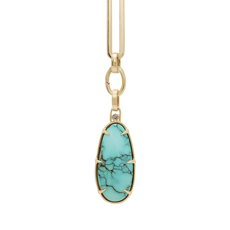 Zoomed in view of a turquoise charm in a bezel setting with claw prongs set in yellow gold with grey diamond accent stone on a mixed link yellow gold chain.