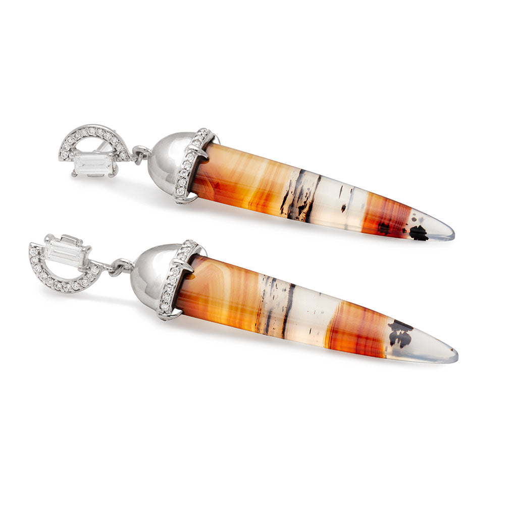 Angled view of a pair of chalcedony drop earrings with a white diamond arc stud at the top set in white gold.