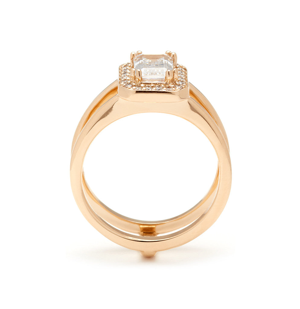Side view of a double banded engagement ring with a white diamond emerald cut diamond surrounded by a white diamond halo set in yellow gold.