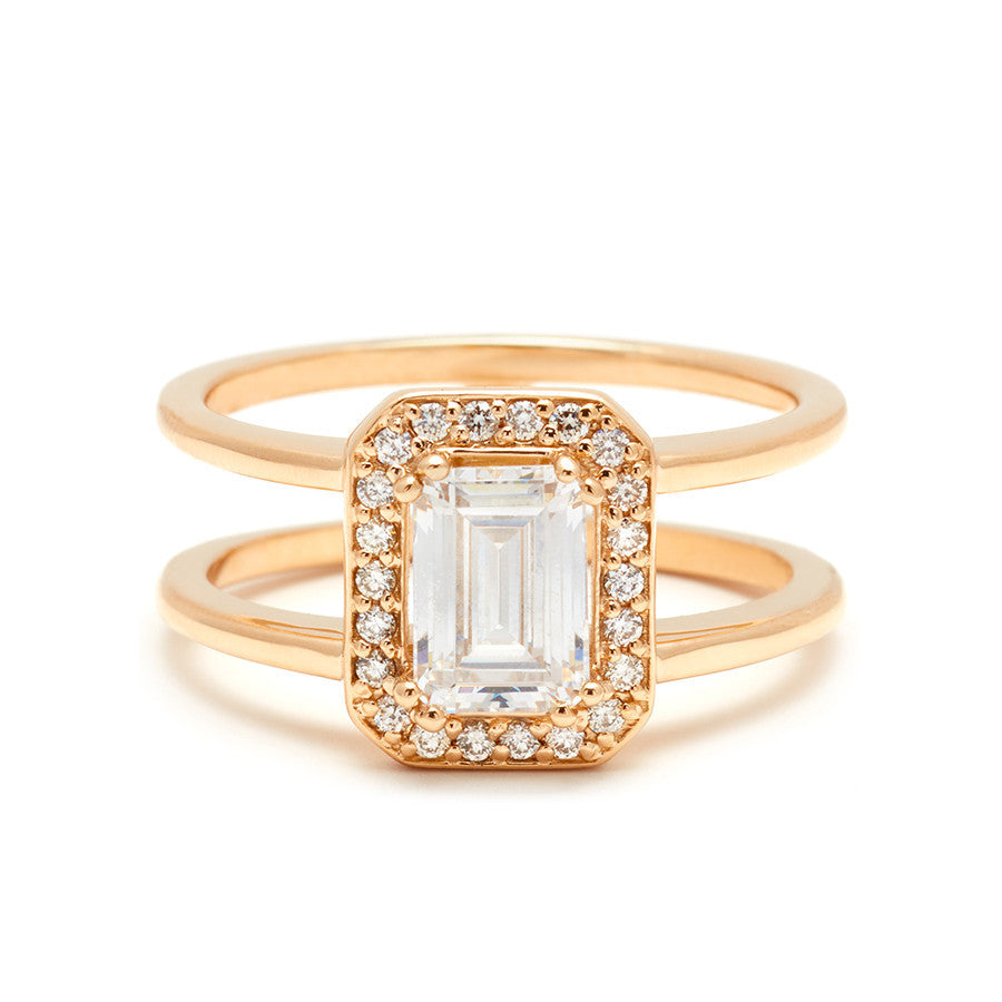 A double banded engagement ring with a white diamond emerald cut diamond surrounded by a white diamond halo set in yellow gold.