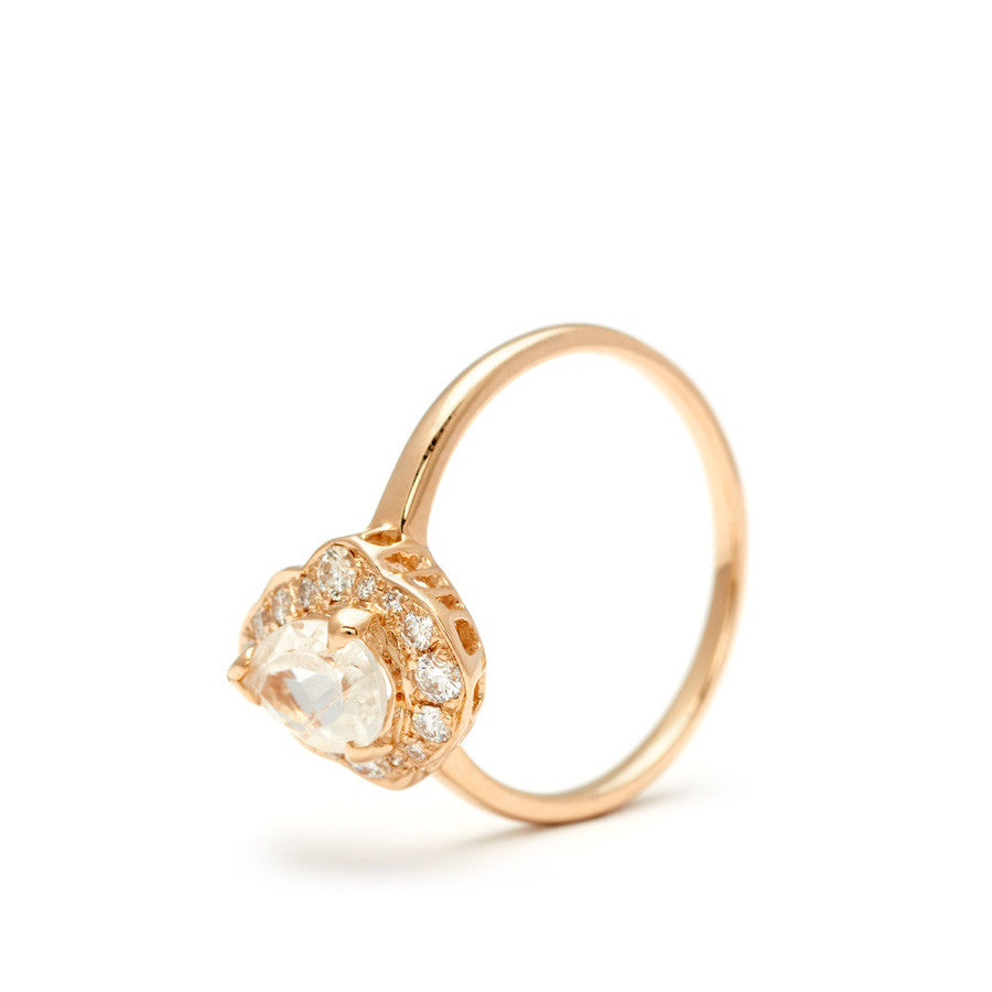 Angled view of a pear shaped rainbow moonstone center ring set in a halo of white diamonds and in yellow gold.
