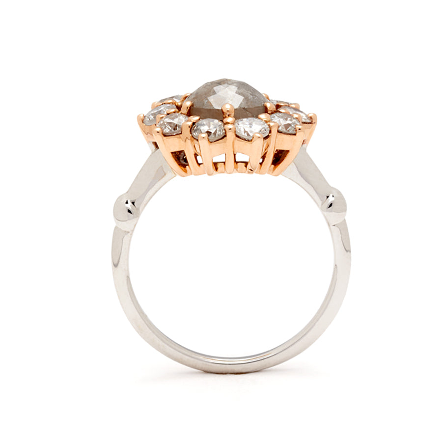 Side view of a ring with a rose cut grey diamond center stone surrounded by round grey diamonds set in a rose gold basket and white gold band.