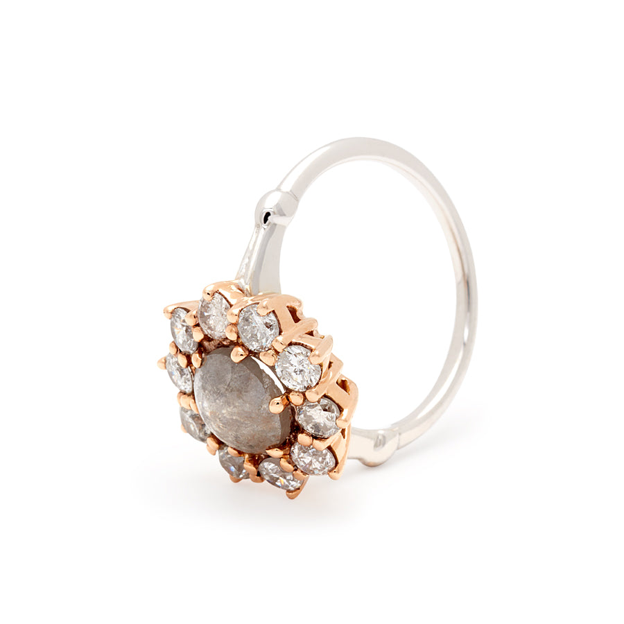 Angled view of a ring with a rose cut grey diamond center stone surrounded by round grey diamonds set in a rose gold basket and white gold band.