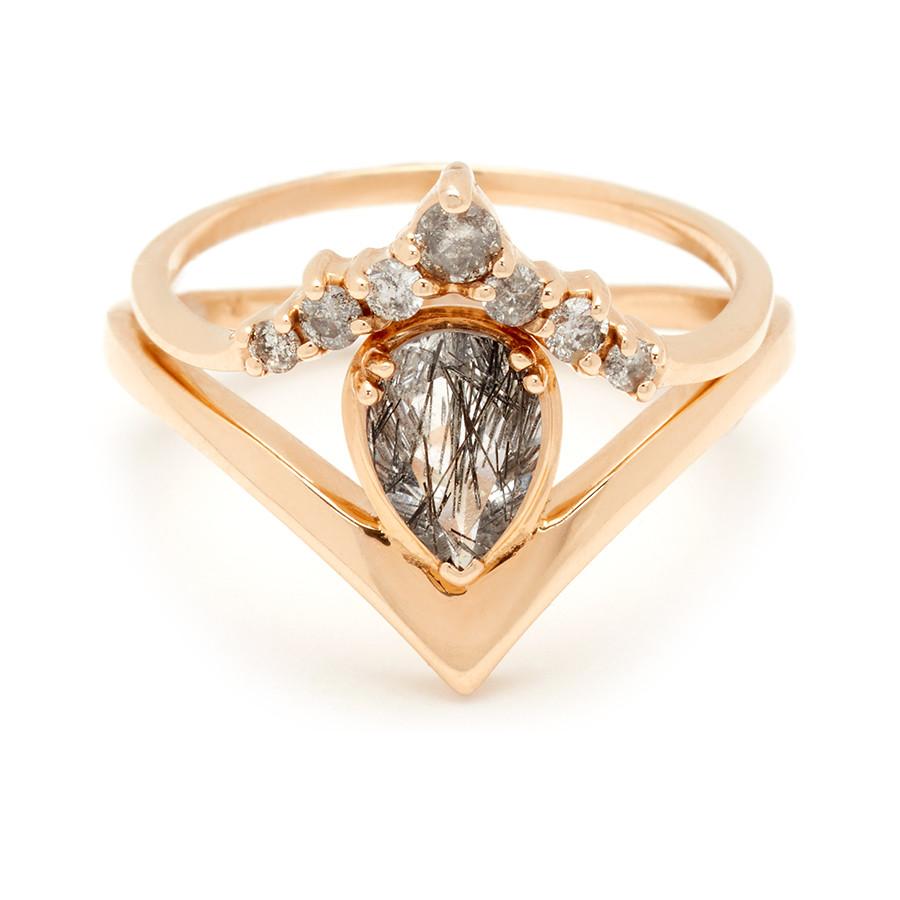 A pear shaped black rutilated quartz ring set in yellow gold stacked beneath a grey diamond chevron band.