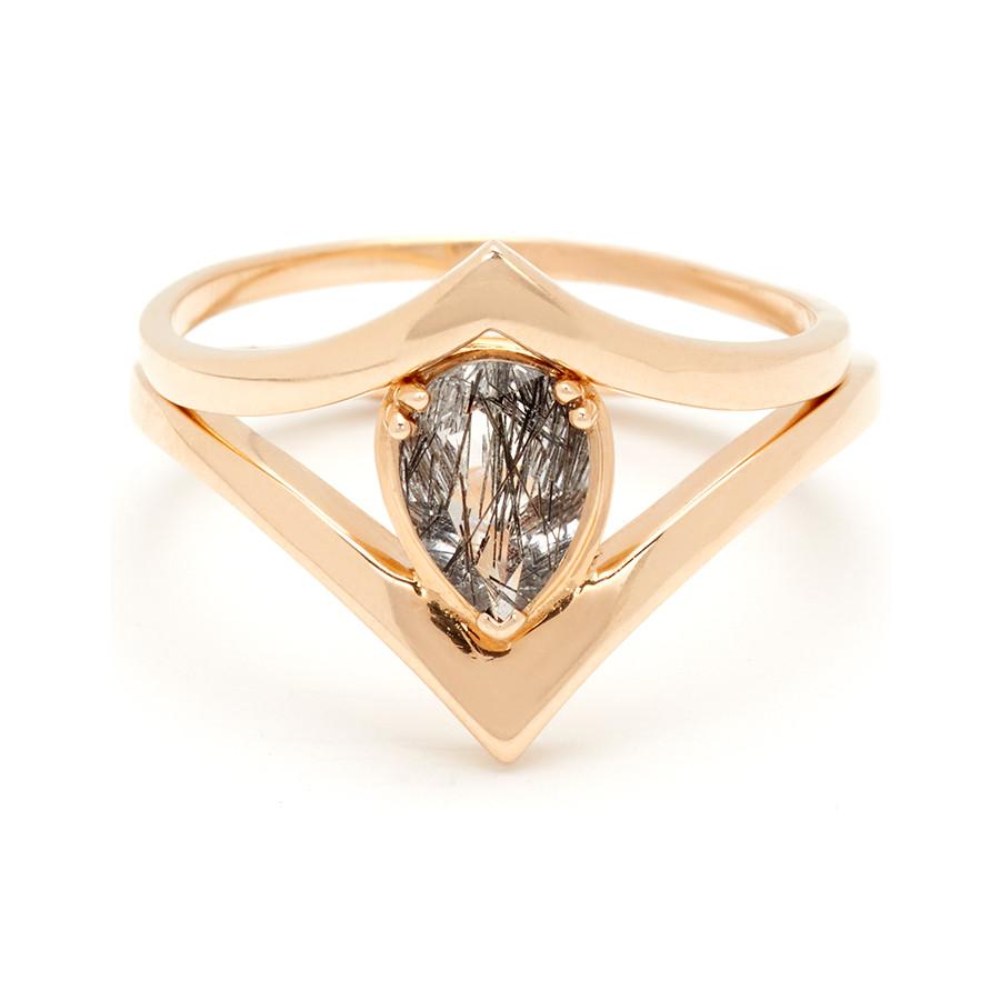 A pear shaped black rutilated quartz ring set in yellow gold stacked beneath a solid gold chevron band.