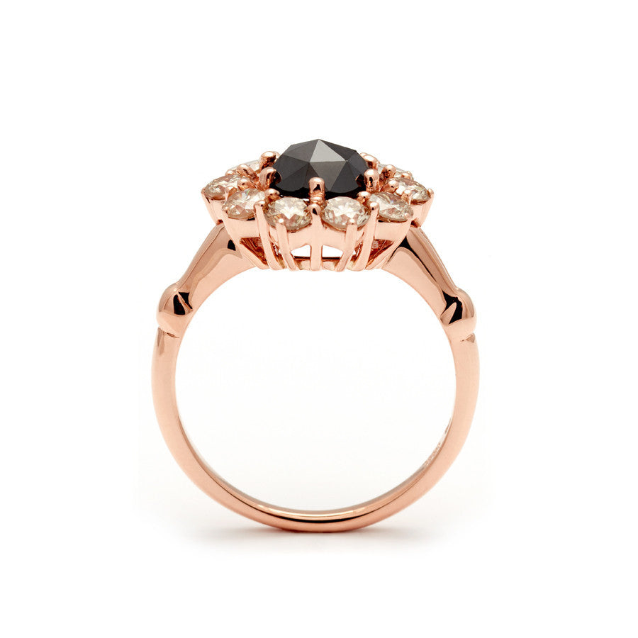 Side view of a ring with a rose cut black diamond center stone surrounded by round champagne diamonds set in rose gold.