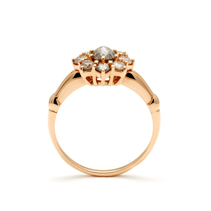 Side view of a cluster engagement ring with a rose cut grey diamond center stone and round grey diamond stones surrounding it set in yellow gold.