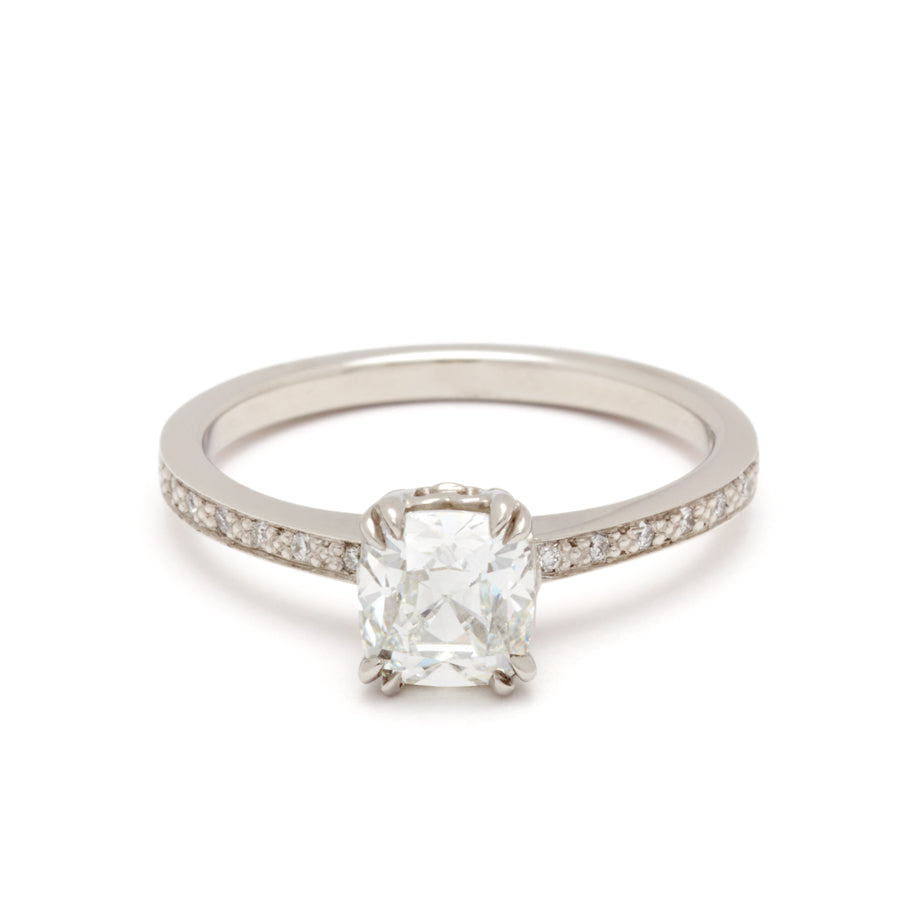 A solitaire ring with a knife edge white diamond with white diamond pave on either side set in white gold.